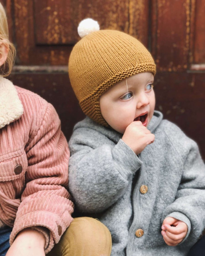 Siddende barn med gul Alberts pilothue på