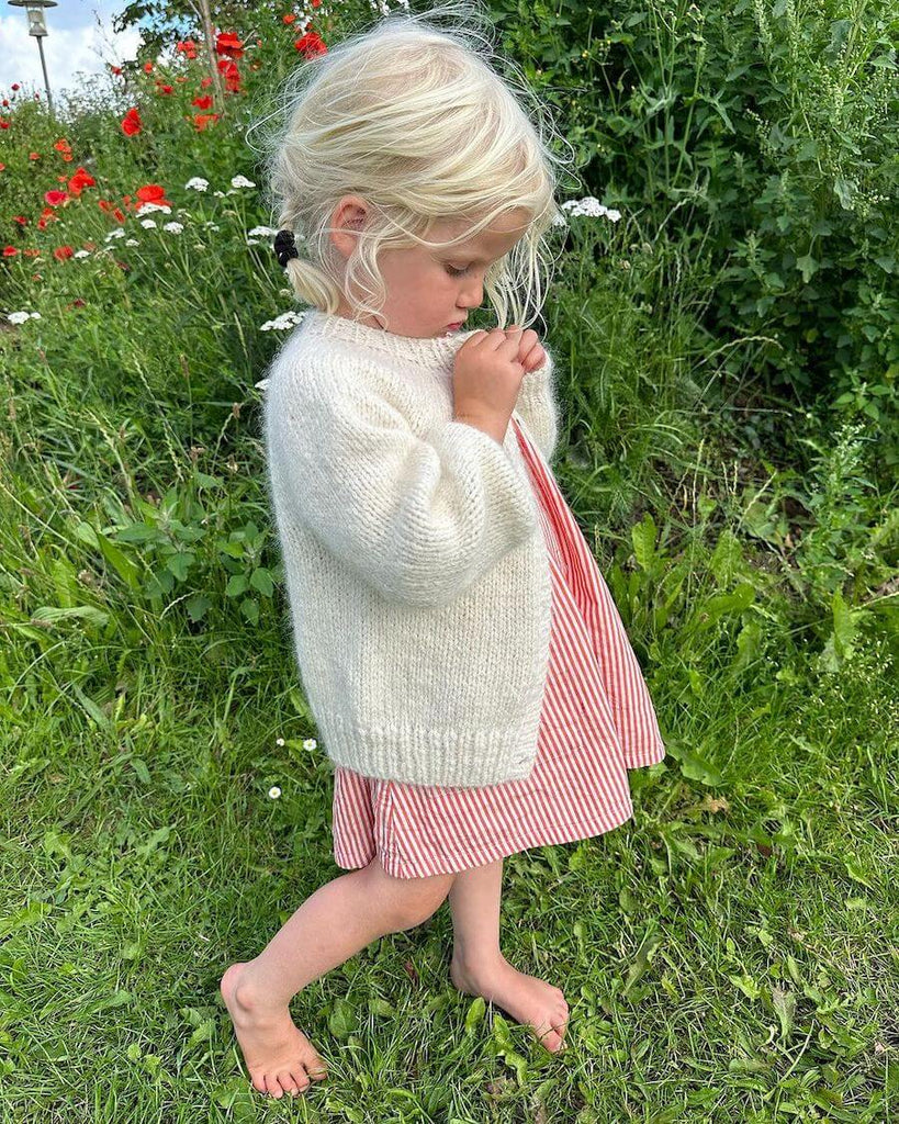 Barn iført hvid Novice Cardigan Mini – Chunky Edition