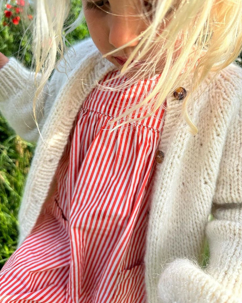 Barn iført hvid Novice Cardigan Mini – Chunky Edition