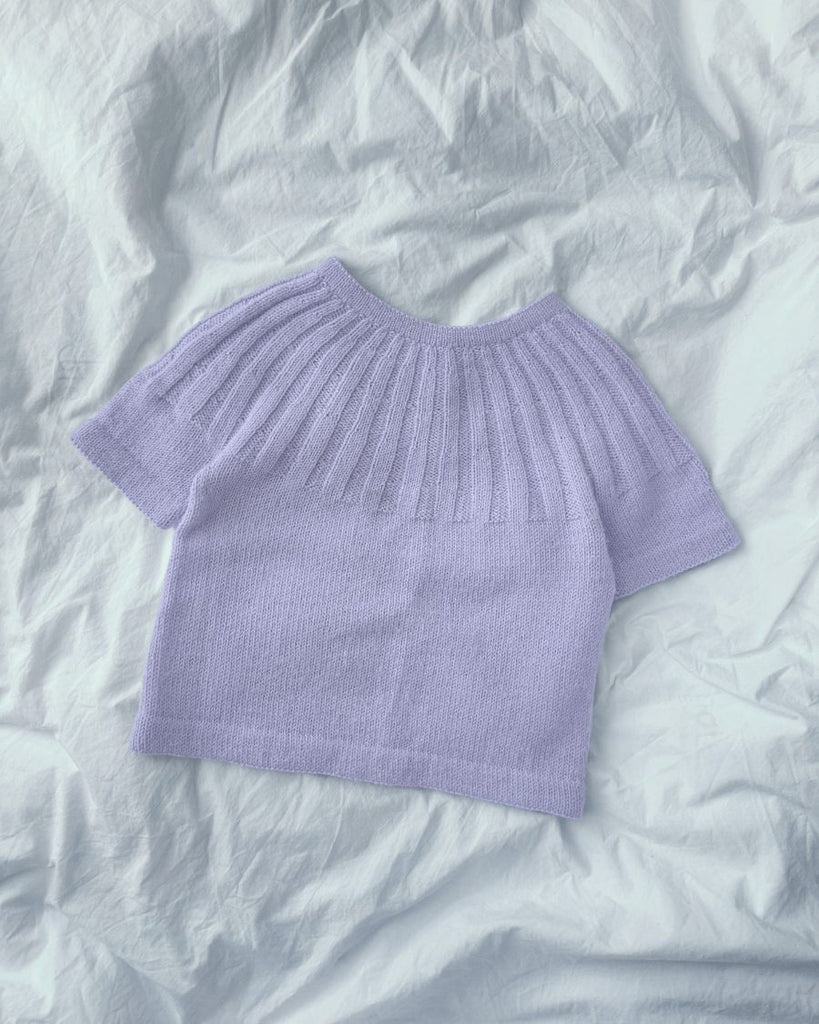 Lilla Sunday Tee Junior liggende på dyne