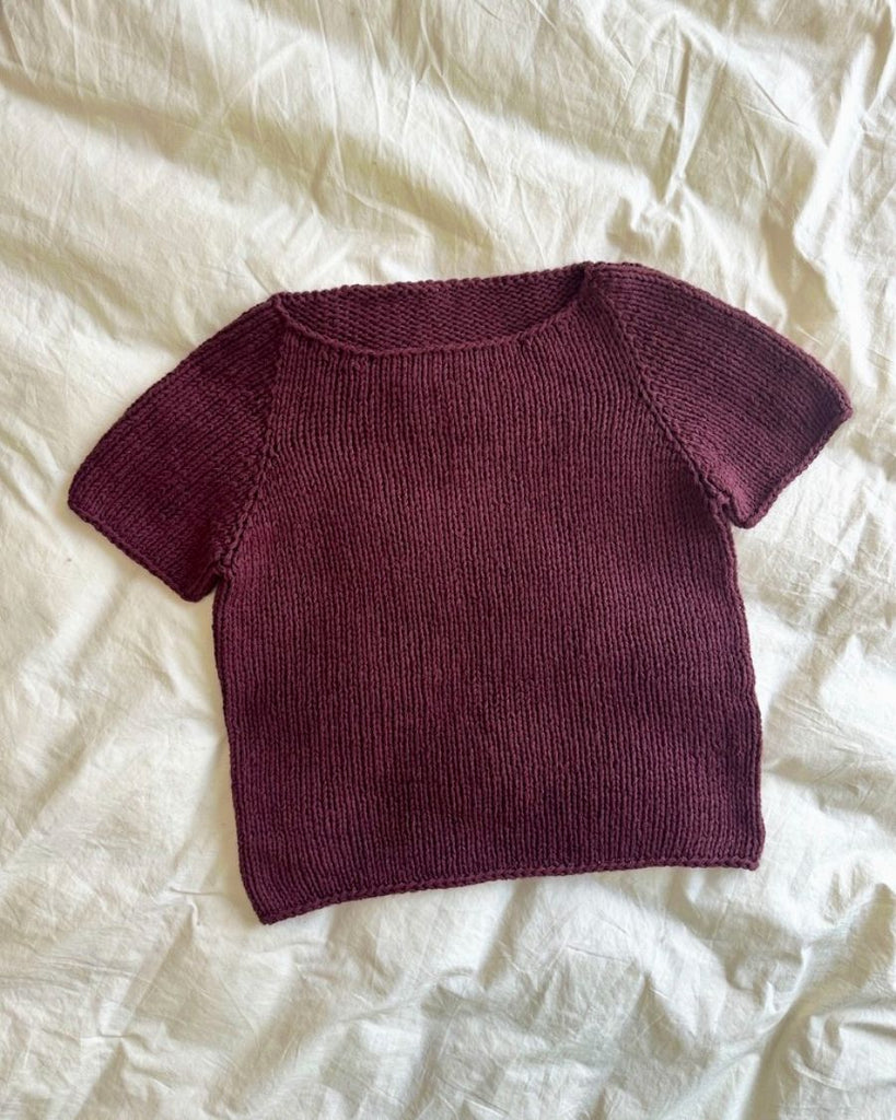 Bordeaux Wave Tee liggende på sengetøj