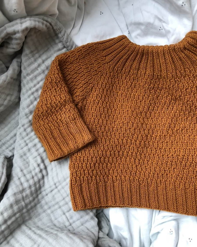 Closeup af liggende orange Alfreds Trøje.