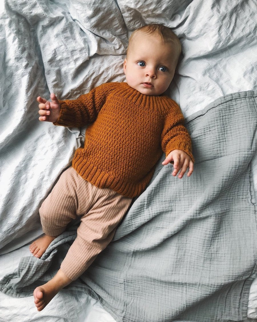Liggende barn iført orange Alfreds Trøje.