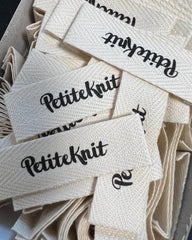 Nærbillede af  mange Petiteknit tekstil labels