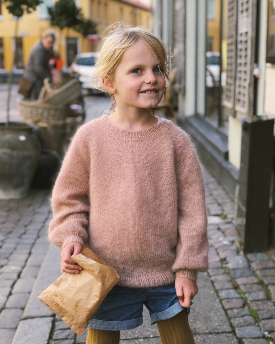 Barn iført lyserød Novice Sweater Junior – Mohair Edition