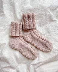 Lyserøde Sunday Socks Junior på dyne