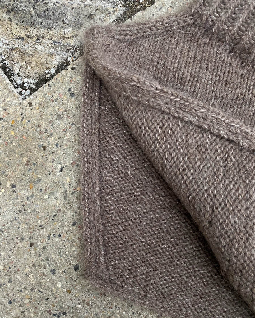 Detaljebillede af brun Zipper Neck liggende på flise