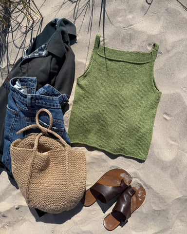 Grøn Emmy Top og brun Julie Bag liggende i sandet