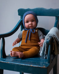 Dukke siddende i stol med dukkestrik tøj