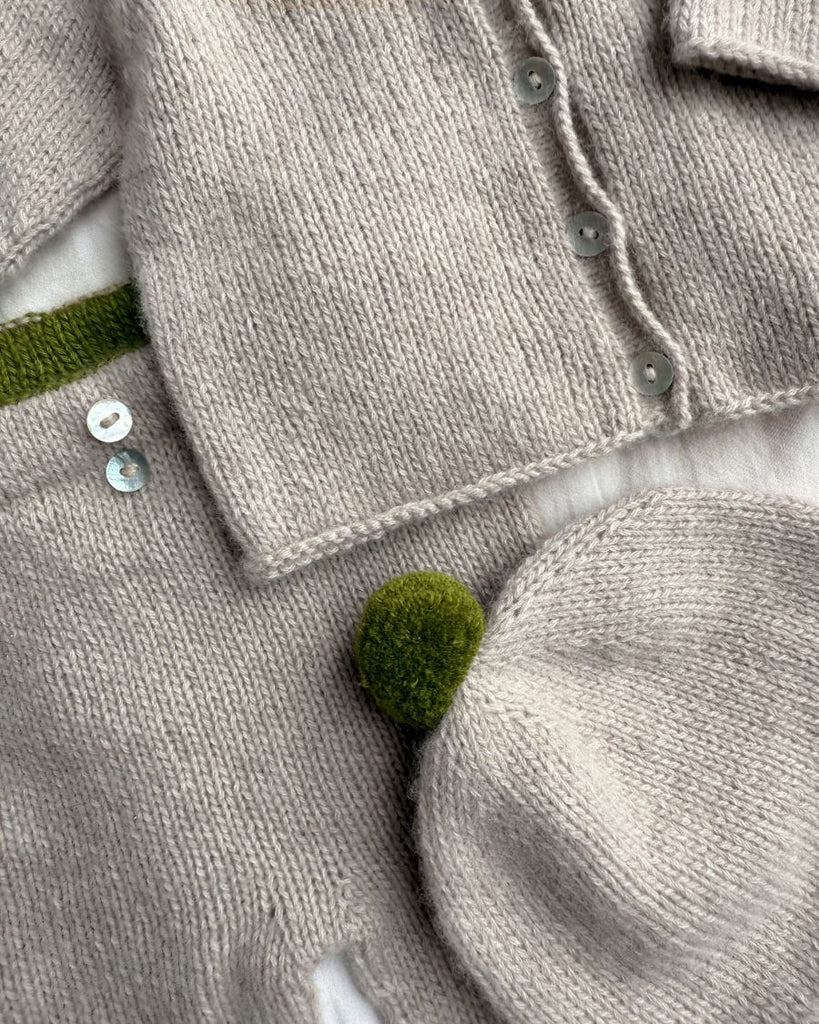 Detaljer fra beige Cleo Baby Set med grøn pompom