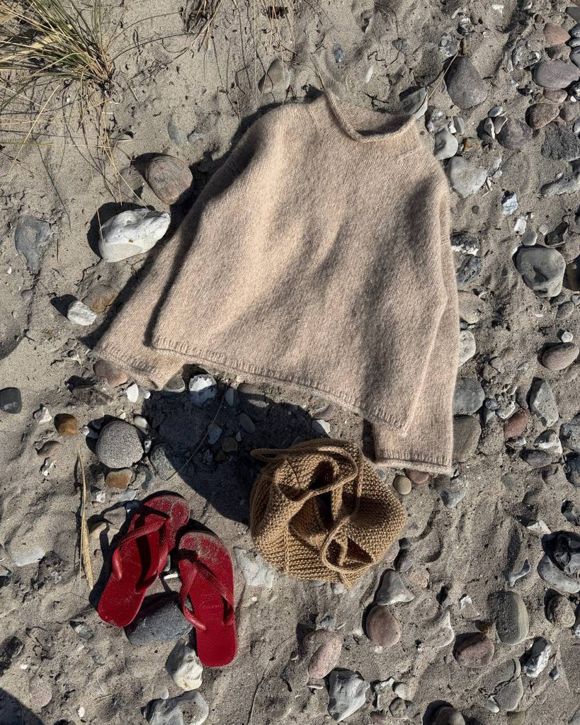 Beige Cloud Sweater liggende på stranden