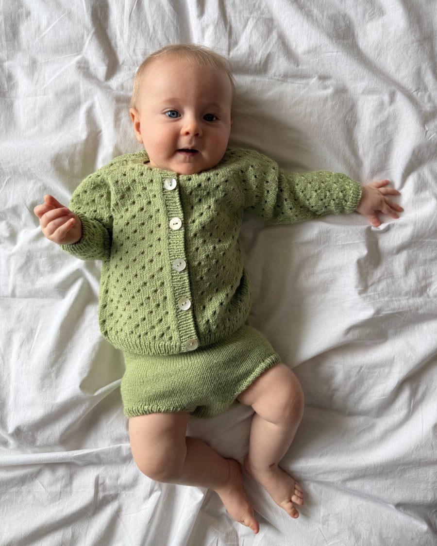 Baby iført grønt Ellens Legsæt