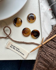 "Gentle wash, dry flat, mend if torn."-label og knapper i vindue