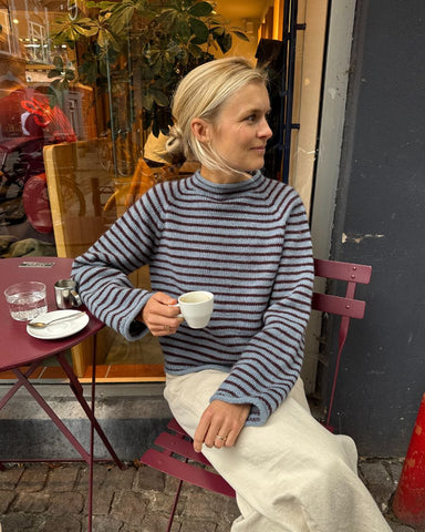 Sidden kvinde iført blå og bordeaux Frankie Sweater
