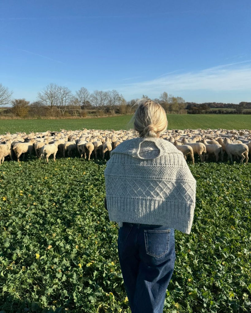 Kvinde med lysegrå Ingrid Sweater over skuldrene set bagfra