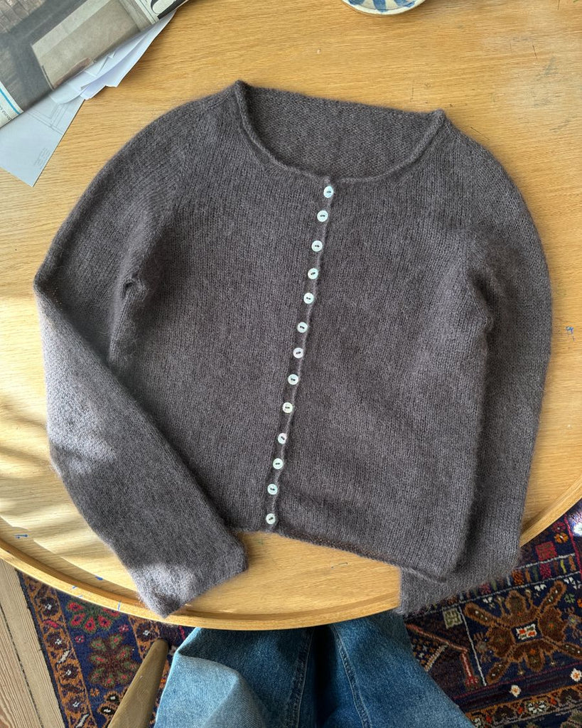 Mørkelilla Ivy Cardigan liggende på sofabord