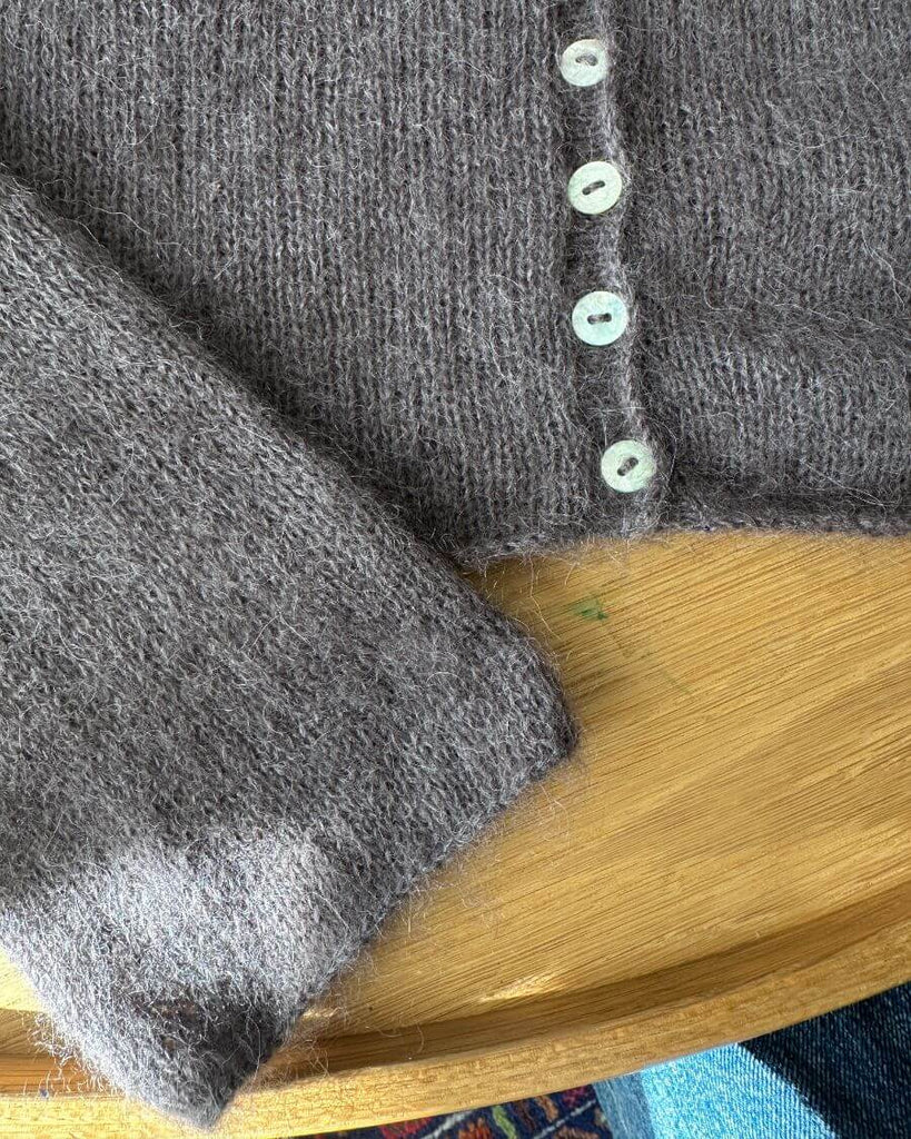 Detaljer ved knapstolpen på mørkelilla Ivy Cardigan 