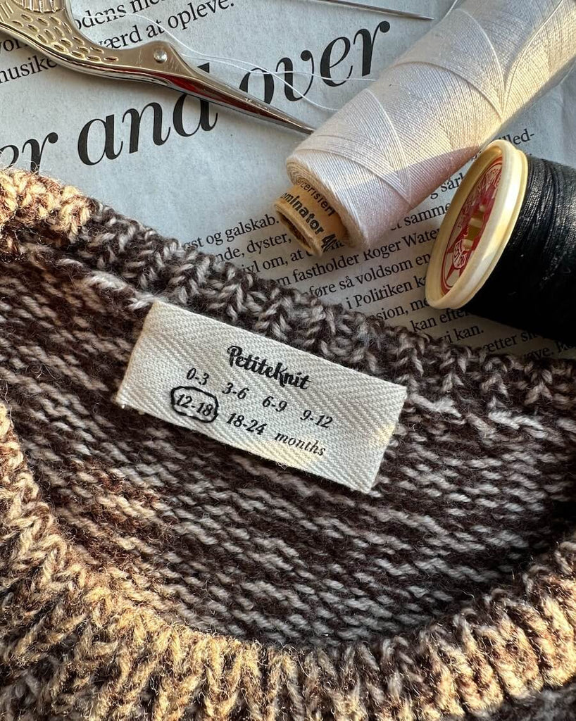 Petiteknit label med babystørrelser i nakken af striktrøje