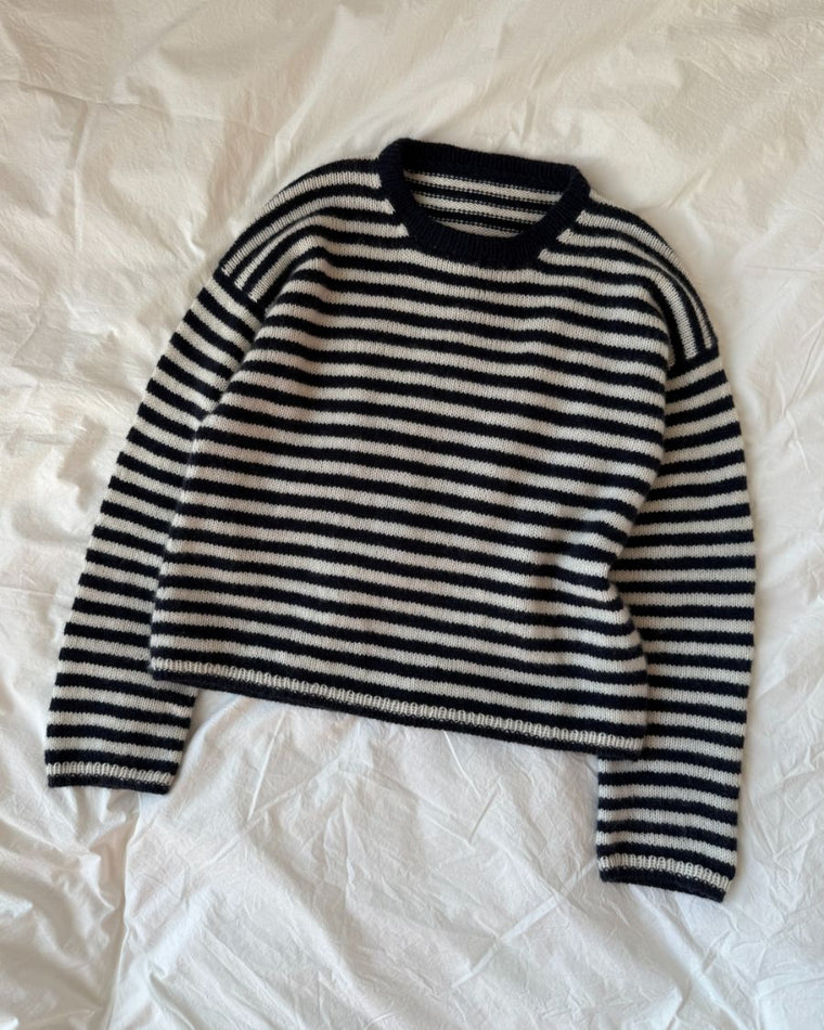 Kvinde iført hvid og blå Olga Blouse siddende på bænk med kaffe