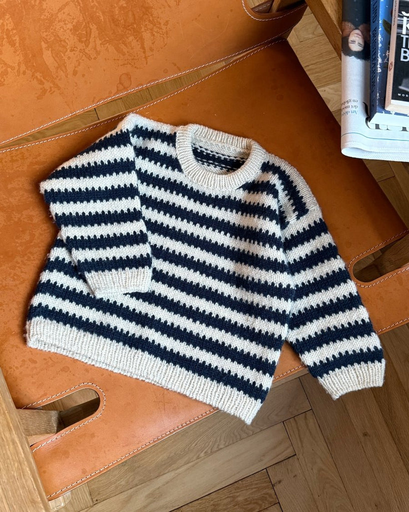 Blå og hvid Otto Sweater Junior liggende på stol