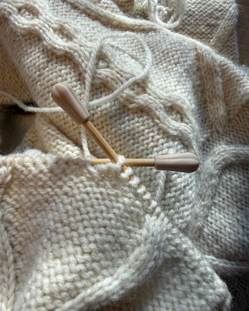 Pindebeskyttere eller maskestoppere på spidsen af pinde på en Saga Sweater der bliver strikket