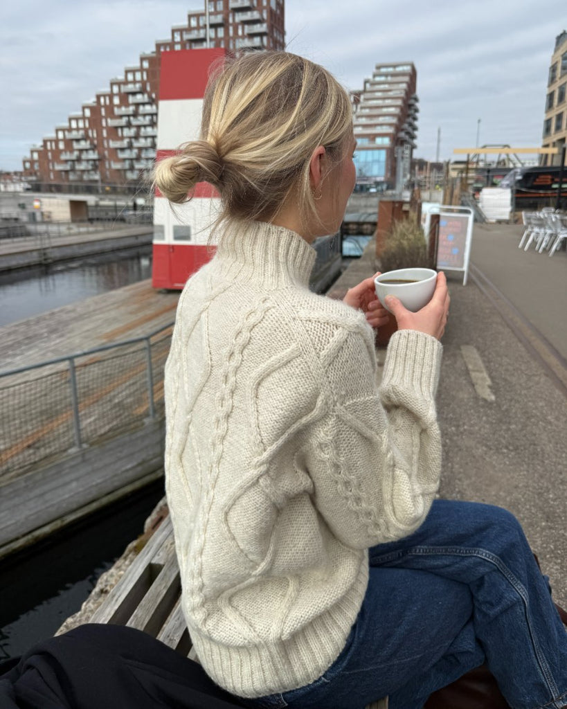 Siddende kvinde iført hvid Saga Sweater set bagfra