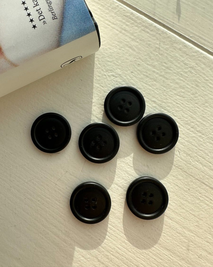 6 galalit knapper i sort på bord