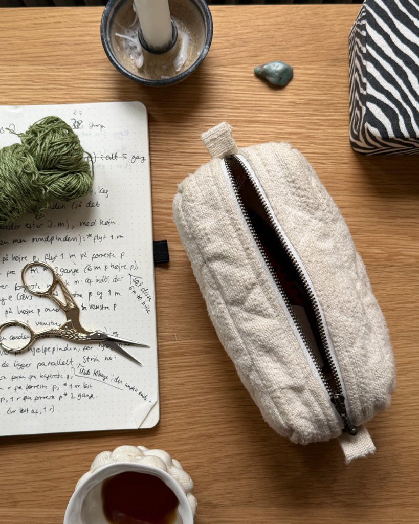 Knitter's Toll Clutch i farven Cloud på skrivebord sammen med noter og storkesaks