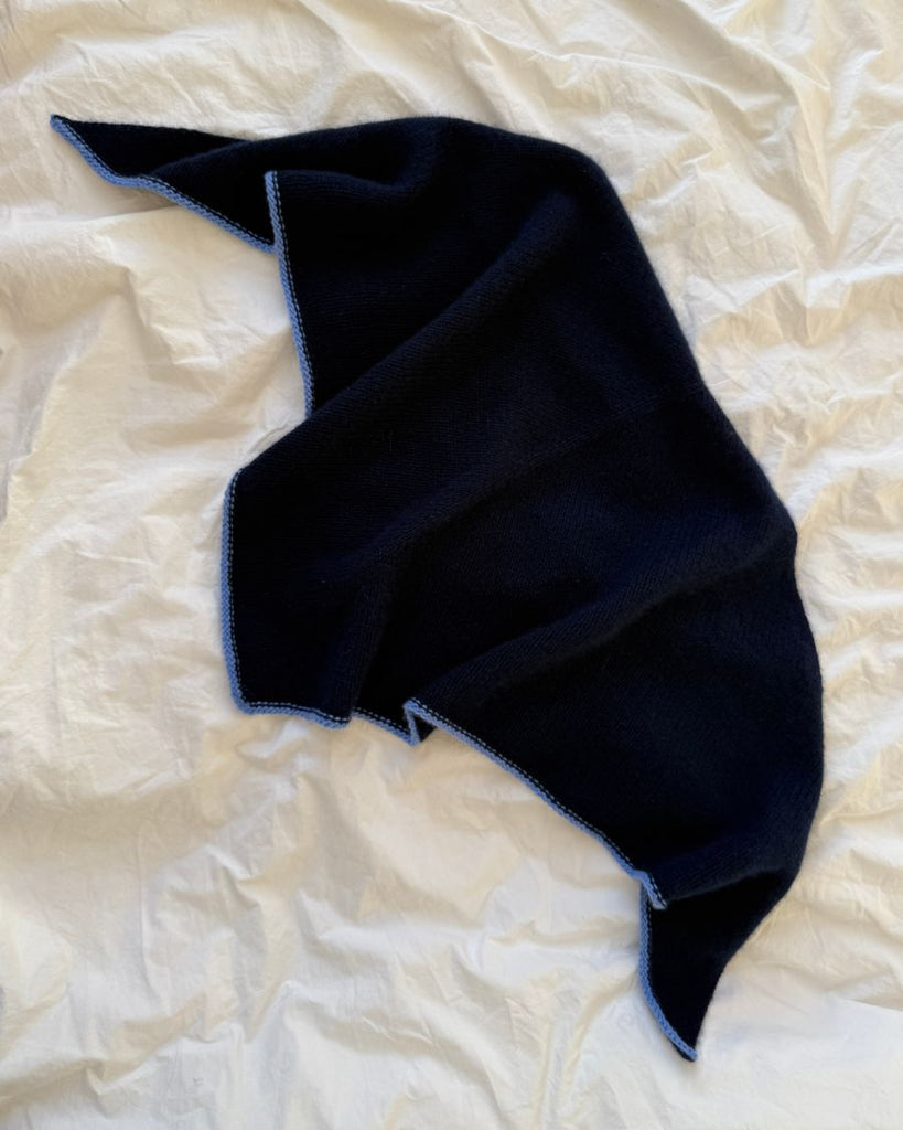 Blåt Uma Scarf liggende på sengetøj