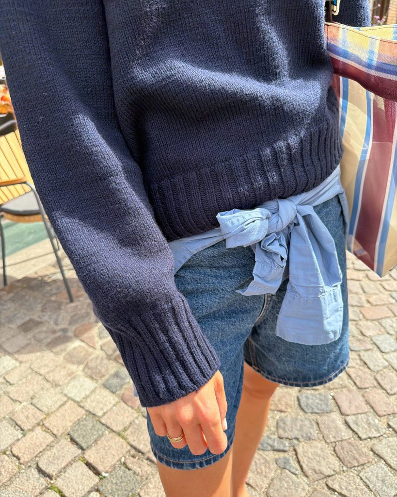 Kvinde iført blå Vega Sweater med fokus på ribkanterne