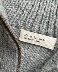 Nærbillede af label med teksten "My mother made me wear this!".