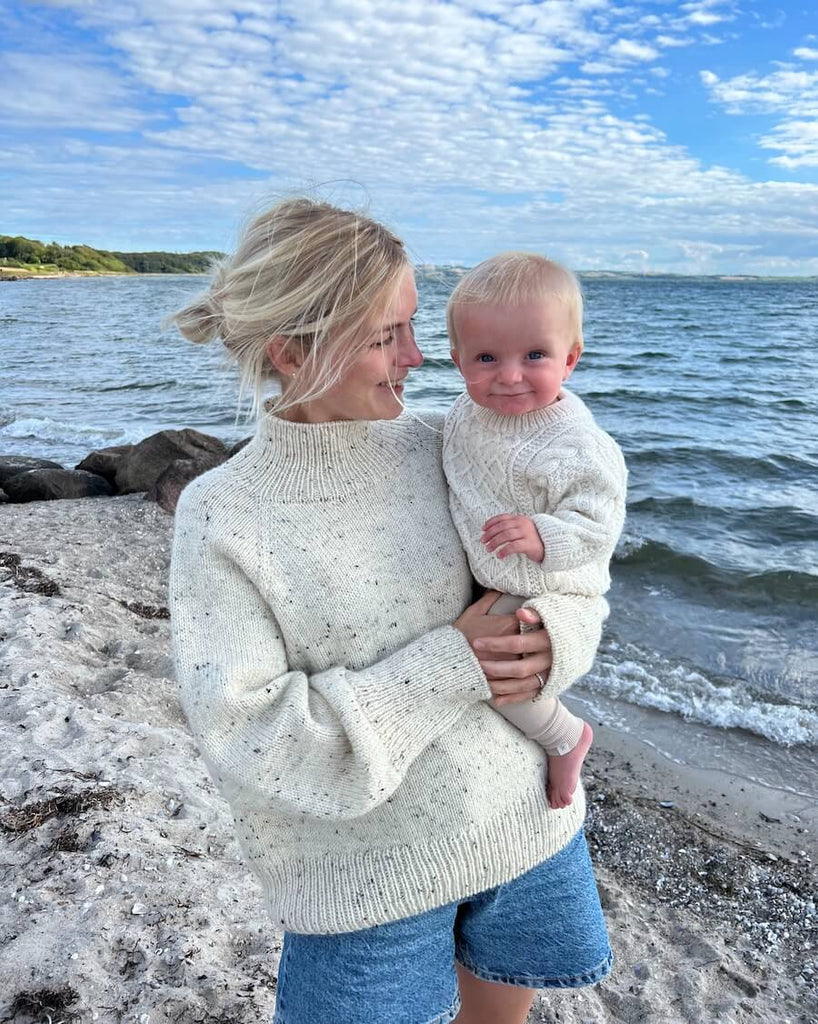 Barn iført hvid Moby Sweater Baby