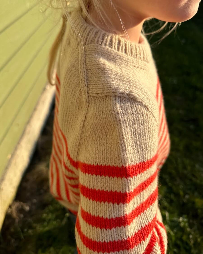 Barn iført hvid og rød Lyon Sweater Junior 