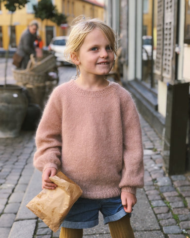 Barn iført lyserød Novice Sweater Junior – Mohair Edition